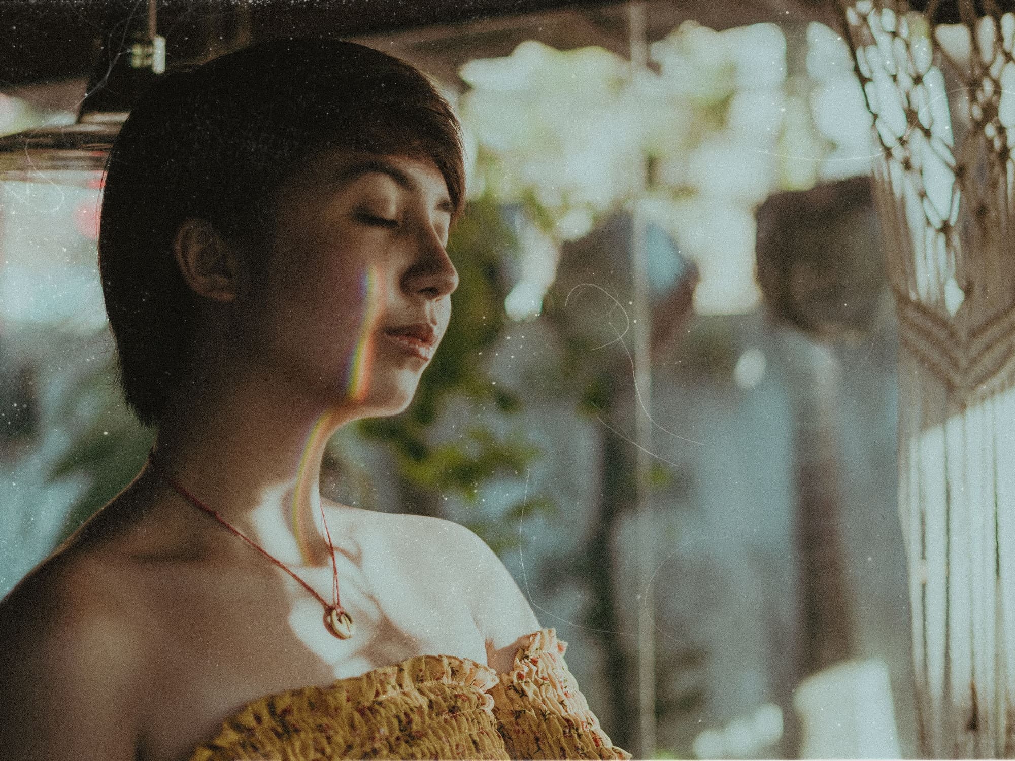 A woman with her eyes closed in hazy window light, warm honey tones across her face and shoulders.